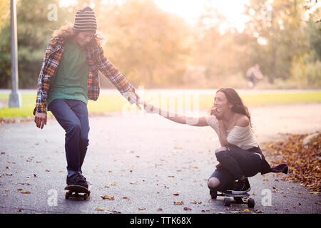 Paar hält Hände beim Skaten auf der Straße Stockfoto