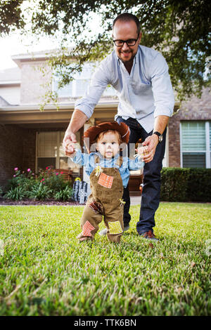 Vater Holding baby Junge verkleidet als Cowboy im Hinterhof Stockfoto