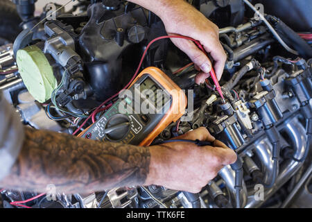 Zugeschnittenes Bild der praktischen Prüfung Auto Motor mit dem Multimeter in der Werkstatt Stockfoto