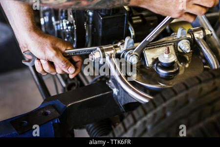 Zugeschnittenes Bild der Hände Befestigungsmuttern von Auto Motor in der Werkstatt Stockfoto