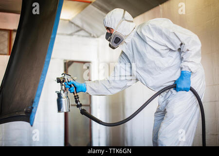 Mechaniker Malerei Fahrzeug teil mit Spritzpistole in Auto Body Shop Stockfoto