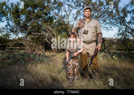 Portrait von Jäger mit Gewehr beim Stehen auf Wiese Stockfoto