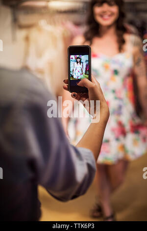 Zugeschnittenes Bild der Hand fotografieren Frau in der Boutique Stockfoto