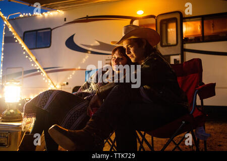 Paar sitzen auf Stühlen gegen Wohnmobil während der Nacht Stockfoto