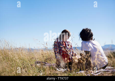 Paar sitzt auf gegen den klaren Himmel Stockfoto