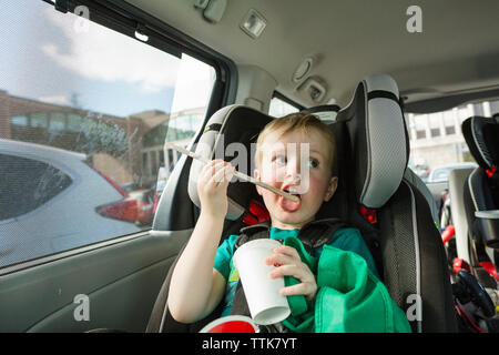 Hübsche jungen lecken Trinkhalm sitzend auf Fahrzeug Sitz im Auto. Stockfoto