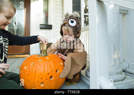 Zwei Kinder untersuchen jack o lantern auf der Veranda vor dem Haus während der Halloween Stockfoto