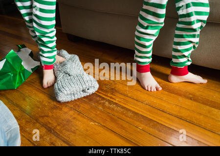 Beine von zwei männlichen Kinder neben Couch am Weihnachtsmorgen Stockfoto