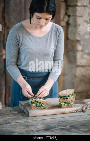 Frau, die Sandwich auf Schneidebrett zu Hause Stockfoto