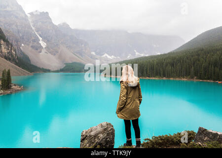 Ansicht der Rückseite des weiblichen Wanderer mit Hand in der Tasche stehen Moraine Lake gegen Berge im Banff National Park Stockfoto