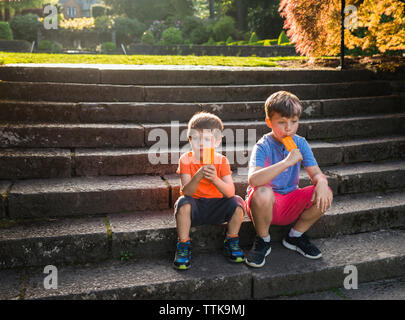 Jungen essen Eis am Stiel beim Sitzen auf Schritte Stockfoto