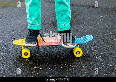 Niedrige Abschnitt der Boy skateboarding auf nassen Straßen Stockfoto
