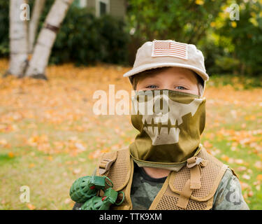 Portrait von cute Boy tragen Armee Soldat Kostüm beim Stehen auf der Wiese im Park Stockfoto