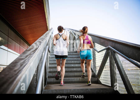 Ansicht der Rückseite des Frauen joggen auf Stufen und Treppen gegen den klaren Himmel Stockfoto