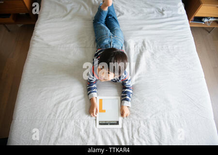 Hohe Betrachtungswinkel von lächelnden Jungen mit digitalen Tablet auf dem Bett Stockfoto