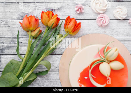 Hohe Betrachtungswinkel von Blumen von Kuchen und Sahne auf den Tisch zu Hause. Stockfoto