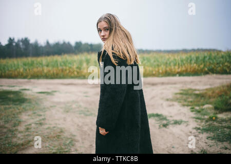 Die Frau stand in der Nähe ein Maisfeld im Regen Stockfoto