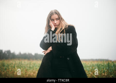 Frau steht in einem Maisfeld bei bewölktem Himmel Stockfoto