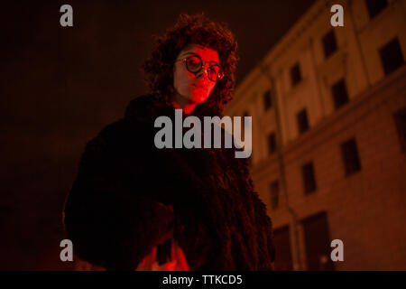 Curly Frau in einem pelzmantel am Abend mit rotem Licht beleuchtet Stockfoto