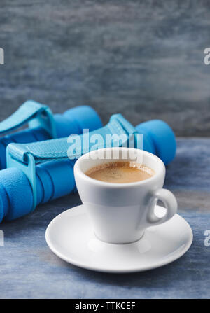 Tasse Kaffee und Kurzhanteln auf Blau Holz- Hintergrund. Kopieren Sie Platz. Stockfoto