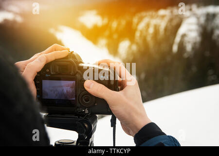 Zugeschnittenes Bild des Menschen fotografieren mit der digitalen Kamera auf schneebedeckte Berge Stockfoto