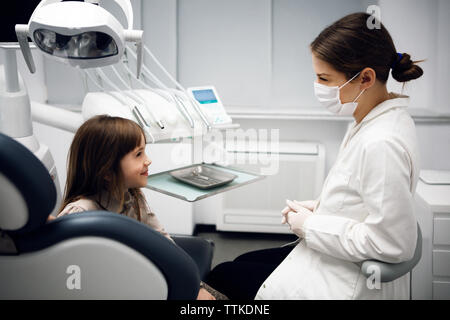 Gerne weiblichen Zahnarzt und Mädchen reden an der Klinik Stockfoto