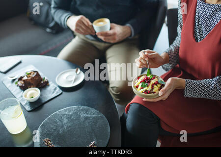 Mittelteil des Geschäfts Paar hält Obstschale und Kaffee im Cafe Stockfoto