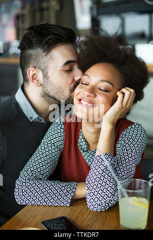 Mann küssen glücklich Frau im Restaurant sitzen Stockfoto