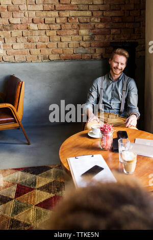Happy Geschäftsmann am Tisch sitzen in der Lobby Stockfoto