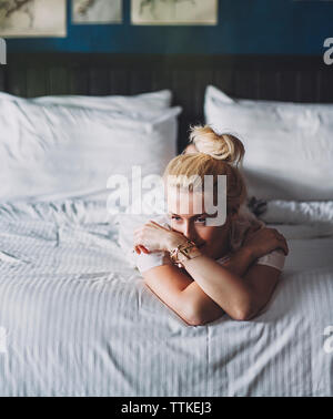 Nachdenkliche Frau auf Bett zu Hause Stockfoto
