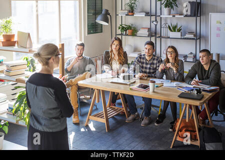 Studenten, die an Lehrer während der Lektion in classsroom Stockfoto