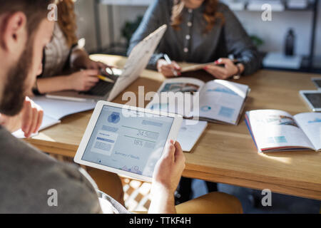 Zugeschnittenes Bild der Mann hält Tablet Computer beim Studieren mit Freunden im Klassenzimmer Stockfoto