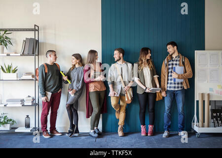 Freunde sprechen, während er gegen die Wand im Klassenzimmer Stockfoto