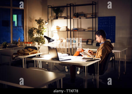 Man studieren während der Sitzung durch Tisch in der Bibliothek Stockfoto