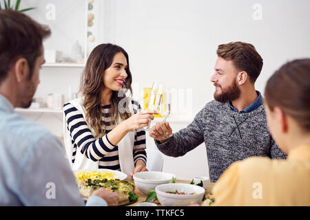 Lächelnd Freunde die feierliche Toast am Esstisch Stockfoto