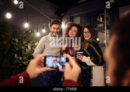 7/8 Hand des Menschen fotografieren Freunde im Hinterhof in der Nacht Stockfoto