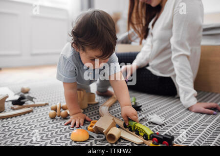 Baby Junge spielt mit minizug durch die Mutter auf Teppich zu Hause Stockfoto