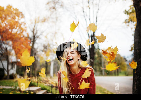 Glückliche Frau, die inmitten der Fliegenden Blätter im Herbst Stockfoto