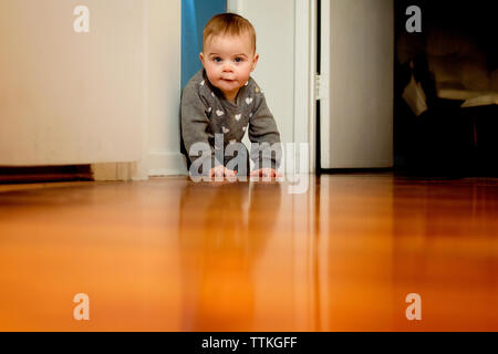 Ein Baby krabbeln auf dem Boden hinter der Tür weg Stockfoto