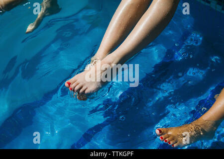 Die Frauen, die Beine baumeln im Pool Stockfoto