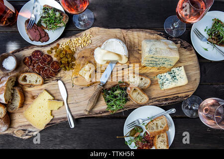 Hohe Betrachtungswinkel von verschiedenen Essen mit Wein auf hölzernen Tisch serviert Stockfoto