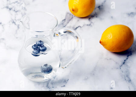 Hohe Betrachtungswinkel der Blaubeeren in Wasser Kanne von Zitronen auf Tisch Stockfoto