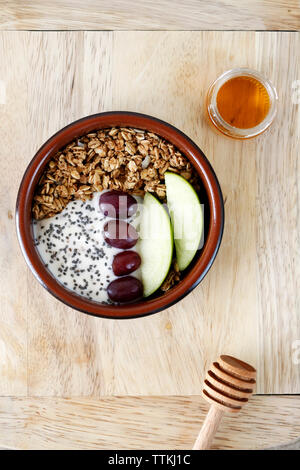 Überblick über das Frühstück in der Schüssel serviert mit Honig auf Holz Schneidebrett am Tisch Stockfoto