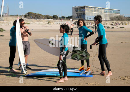 Jungen Surfern Teens das Tragen von Neoprenanzügen mit surfbretter stehen und reden zusammen am Strand von Jandía Porto Portugal Europa EU-KATHY DEWITT Stockfoto