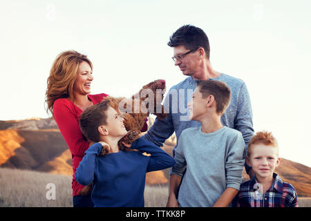 Glückliche Familie mit Hund steht auf gegen den klaren Himmel Stockfoto