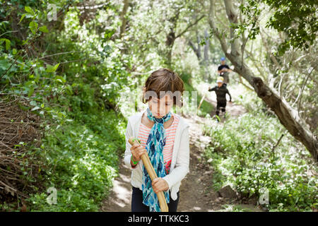 Girl holding Stock beim Gehen auf Wanderweg im Wald Stockfoto