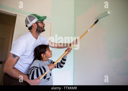 Vater, Tochter in der Malerei Wand mit farbroller zu Hause Stockfoto