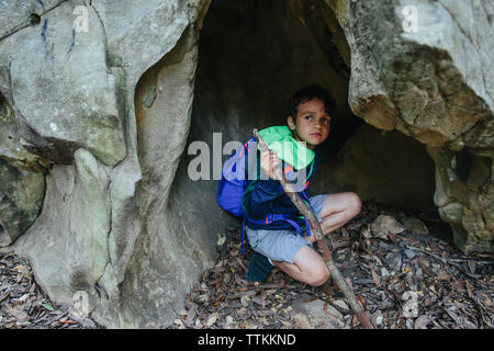 Junge mit Rucksack weg schauen, während sich in Felsen Stockfoto