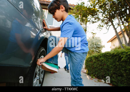 Junge anziehen Reifen mit Schraubenschlüssel an der Einfahrt Stockfoto