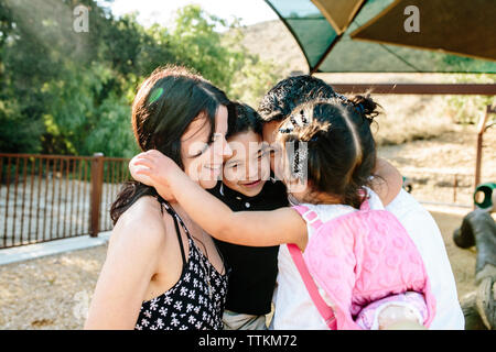 Glücklich, multi-ethnischen Eltern Kinder umarmt, während in PARK-Stellung Stockfoto